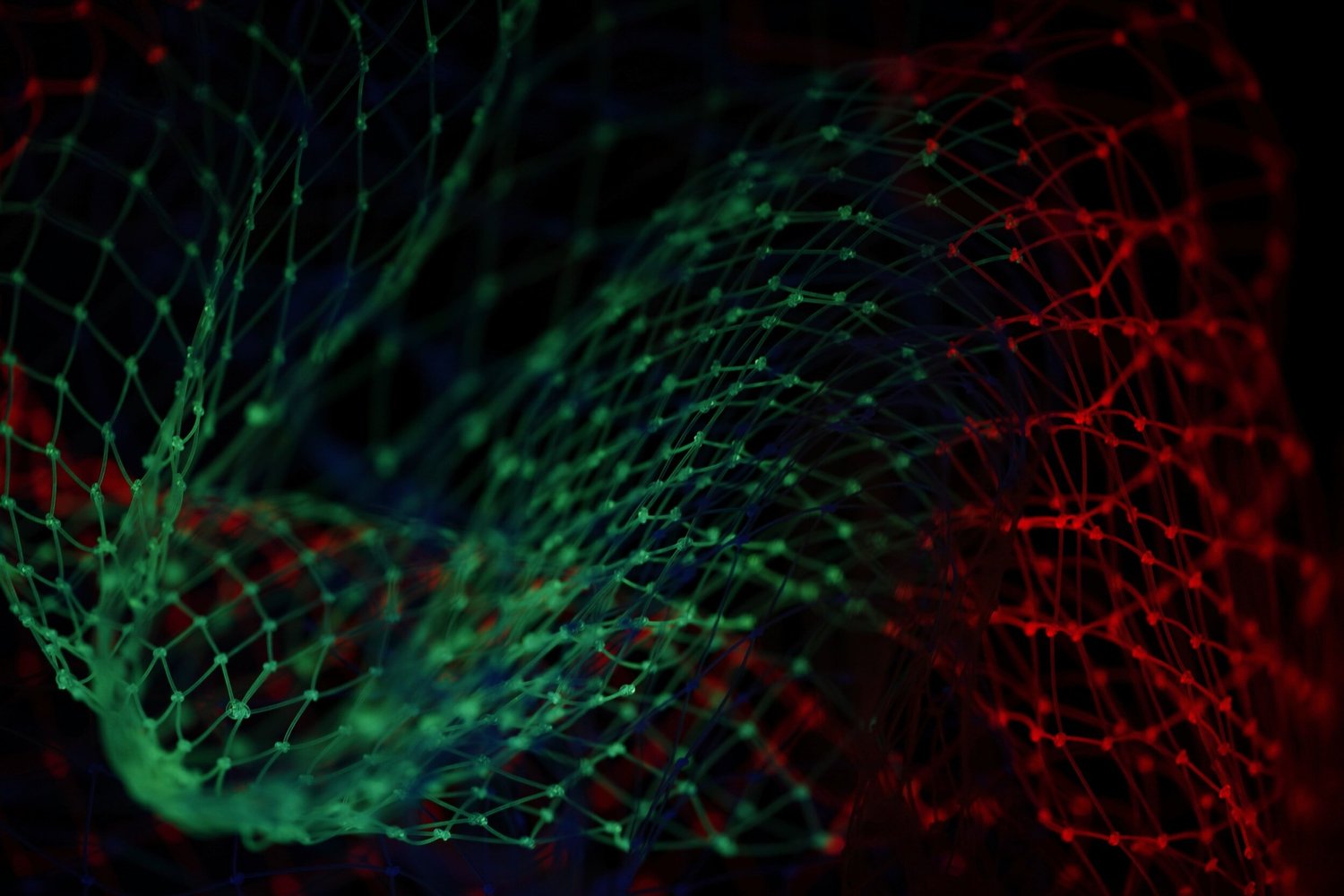 Abstract close-up of a green net on the left and a red net on the right, illuminated against a black background.